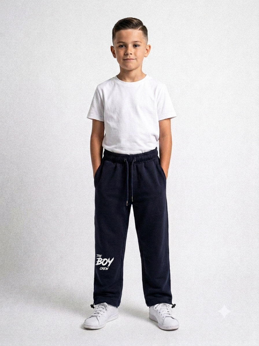Boy wearing navy The Boy Crew joggers with white tee and sneakers, hands in pockets, full-length front view