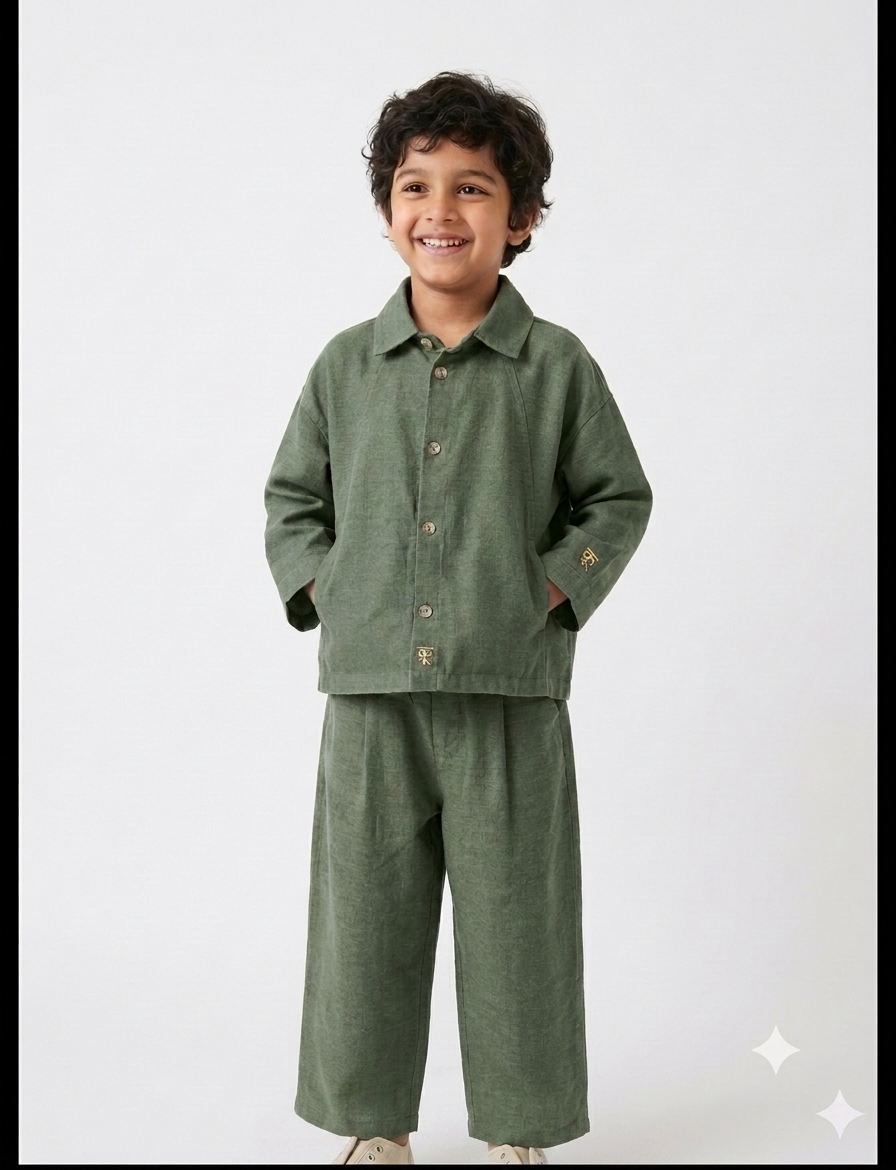 Boy wearing navy linen co-ord set with button-up shirt and wide-leg trousers, smiling against white background