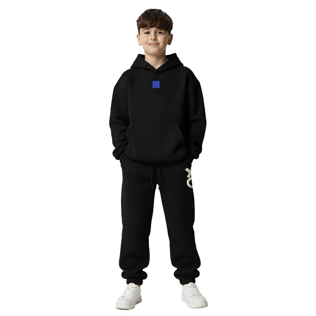 Boy wearing black tic-tac-toe hoodie and jogger set with blue chest patch and XO print on leg