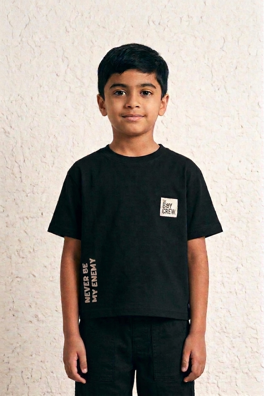 Boy wearing black Bad Bunny tee front view with chest patch label and 'Never Be My Enemy' side text